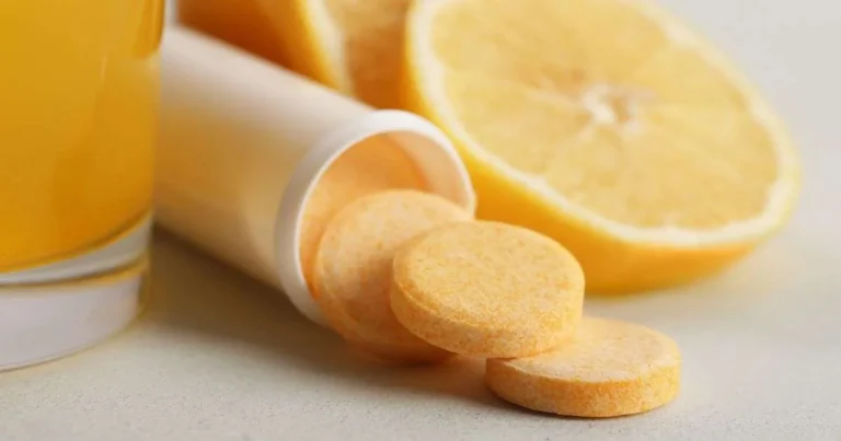 Comprimidos efervescentes de vitamina C saindo do frasco ao lado de laranja cortada e copo com suco