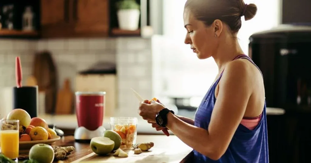 Mulher em uma cozinha preparando um suco saudável com ingredientes naturais como maçã e gengibre, ilustrando a escolha de alimentos anti-inflamatórios para a dieta.