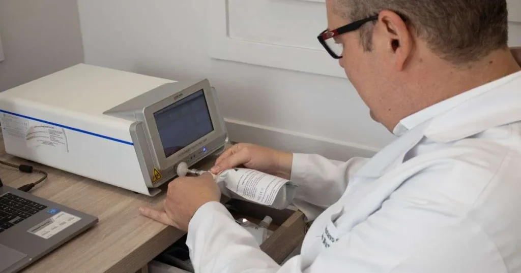 Médico de jaleco branco operando aparelho de teste respiratório para análise de hidrogênio e metano expirado em consultório