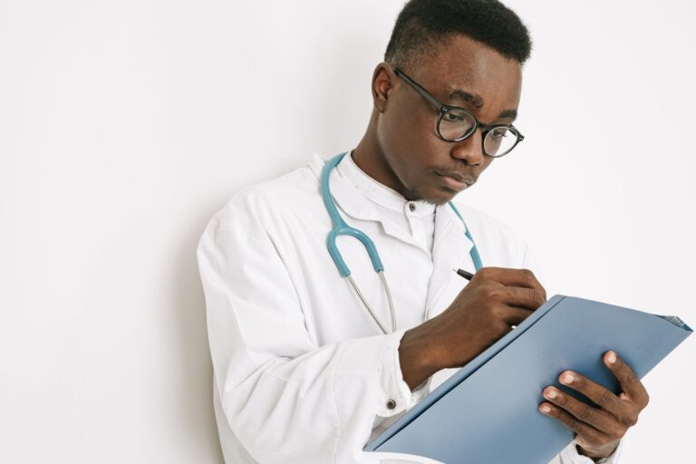 Médico registra informações em prontuário durante consulta.